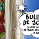 Une bulle de style comique sur fond bleu indique "BULLES DE JOUY QUAND LA TOILE DE JOUY RENCONTRE LA BD". À gauche, un tissu provenant du Musée de la Toile de Jouy représente une scène historique avec un homme et une femme en habits d'époque colorés. - Musée de la Toile de Jouy