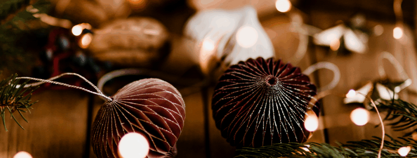 Des décorations de Noël rustiques avec des branches de pin, des baies rouges, des noix et des ornements en papier brun sont éparpillées sur une surface en bois, illuminée par de chaleureuses guirlandes lumineuses - un atelier créatif festif pour célébrer Noël. - Musée de la Toile de Jouy