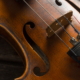 Gros plan d'un violon en bois, montrant les cordes, le chevalet et les détails du trou de fa, avec une finition brune chaude et riche et des veines de bois visibles - rappelant l'art présenté au Musée de la Toile de Jouy. - Musée de la Toile de Jouy