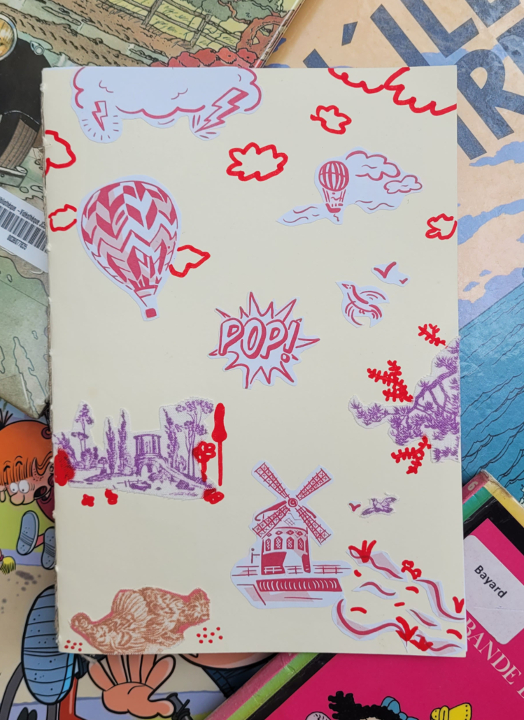La couverture du carnet présente des croquis rouges et violets de montgolfières, de nuages, d'un moulin à vent, d'arbres et du mot "POP" - évoquant l'esprit ludique des Journées européennes du patrimoine - sur un fond clair avec des bandes dessinées et des livres en dessous. - Musée de la Toile de Jouy