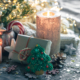Une scène festive avec des bougies allumées, un biscuit en forme d'arbre de Noël, un cadeau emballé, des pommes de pin, des ornements et des lumières scintillantes sur une surface en bois rustique. Des confettis étincelants et des décorations douillettes complètent l'atmosphère de vacances. - Musée de la Toile de Jouy